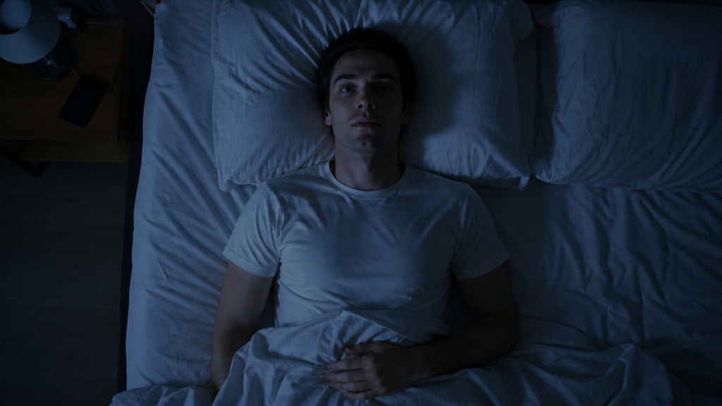can sleep paralysis kill you — person lying awake in dark bedroom unable to move